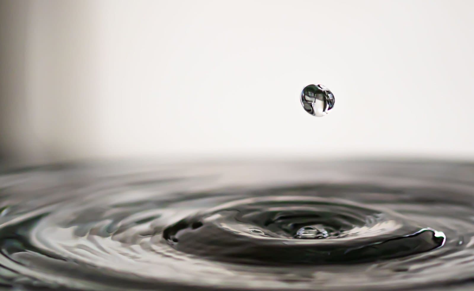 Close de gota de água em superfície líquida